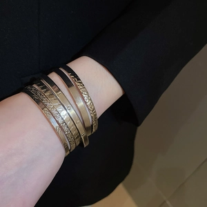 Set of 5 minimalist gold bangles with LOVE engraving and hammered texture on black suit