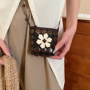 Detail of handcrafted coconut shell crossbody bag with a white resin flower accent