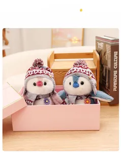 Close-up of pink and blue penguin plush set with knitted hats and scarves in a gift box