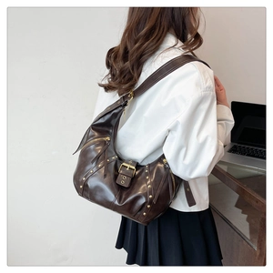 Detail of dark brown vintage dumpling bag with metal rivets and soft leather texture