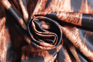 Close-up of leopard print fabric showing fine twill texture and silky sheen finish