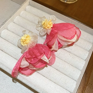 Close-up of pink and beige fabric flower earrings with pearls in a jewelry box