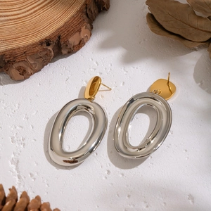 Detail of two-tone gold and silver oval drop earrings on a rustic textured background