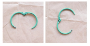 Detail view of mint green metal loose-leaf ring in open state on kraft paper
