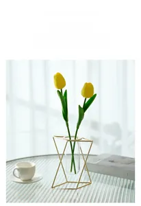 Detail of geometric gold metal frame vase with glass tube and yellow tulips