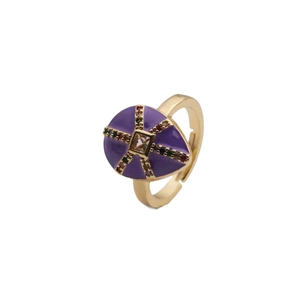 Gold plated teardrop ring with purple enamel and zircon inlay on a white background