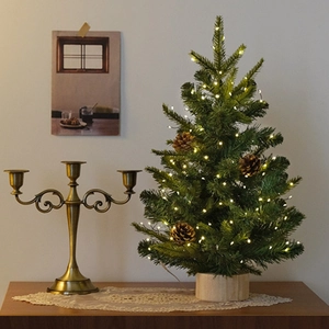 Mini artificial Christmas tree on wooden base with pine cones and warm LED string lights
