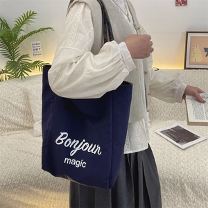 Detail view of navy canvas tote bag featuring white Bonjour magic print and wide shoulder strap