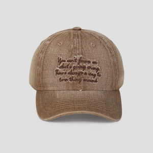 Détail de la casquette de baseball en coton marron délavé avec citation brodée