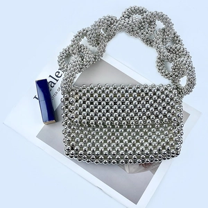 Close-up of a silver beaded evening bag with large bead handle and metallic texture