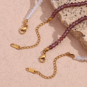 Detailed macro view of purple and cream faceted beads with a gold K18 clasp and extender chain