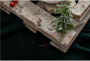 Macro detail of wooden Christmas candle holder with natural bark, pine needles and snow