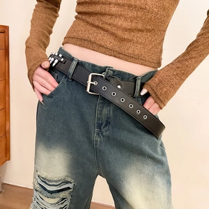 Détail d'une ceinture en cuir noir avec œillets argentés et clous métalliques en balle