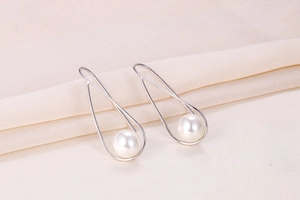 Detail of elegant S925 silver pearl drop earrings with artistic wire-wrapped frames