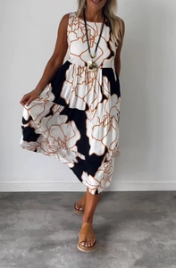 Sleeveless maxi dress with bold black, white, and brown floral prints and waist tie