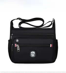 Detail of black multi-pocket nylon crossbody bag with zipper compartments and fashion logo