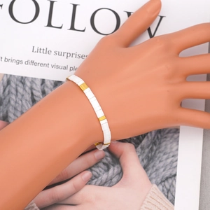 Bohemian Tila bead bracelet with white enamel and gold spacers on a female wrist