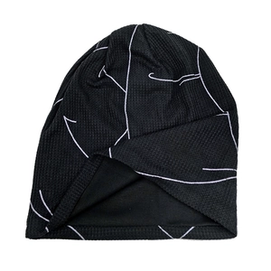 Detail of black knitted beanie with white geometric lines and ribbed fabric texture