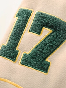 Détail du patch en chenille numéro 17 avec broderie jaune sur une veste en maille beige