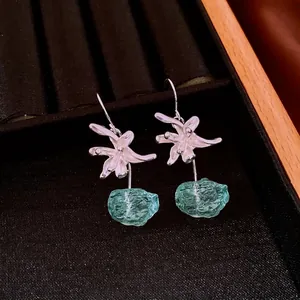 Elegant floral silver earrings with turquoise resin pendant in a black velvet display