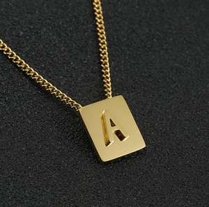 Macro detail of gold 18K stainless steel square pendant with embossed letter A