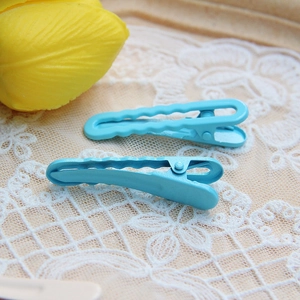 Close-up of blue wavy metal hair clips with matte finish on delicate beige lace fabric