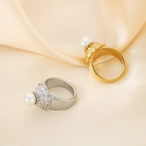 Dettaglio di anelli testurizzati in oro e argento con perle su elegante seta champagne