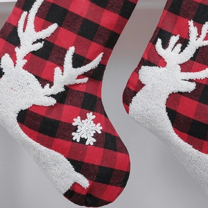 Detail of red and black plaid Christmas stockings with white embroidered reindeer and snowflakes
