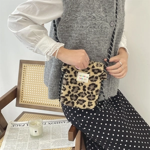 Petit sac bandoulière en peluche léopard marron porté par un mannequin en intérieur