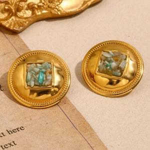 Gros plan de boucles d'oreilles rondes dorées 18K avec incrustations de pierres