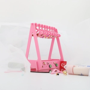 Pink acrylic earring organizer featuring mini clothes hangers on a studio background