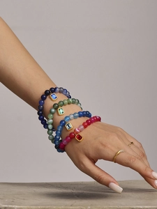 Detail of four colorful agate beaded bracelets with gold-edged gemstone charms