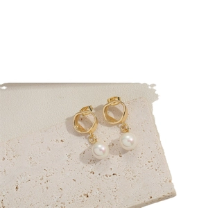 Elegant gold drop earrings with irregular hoops and white round pearls on stone