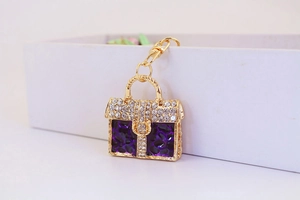 Close-up of golden keychain with purple leopard print handbag pendant and sparkling crystals