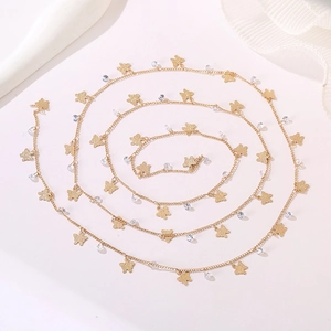 Macro shot of gold butterfly necklace with crystal beads on a soft white fabric background