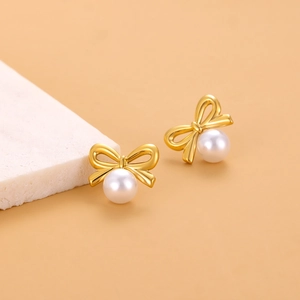 Vue détaillée des boucles d'oreilles nœud plaquées or 18K avec perles blanches rondes