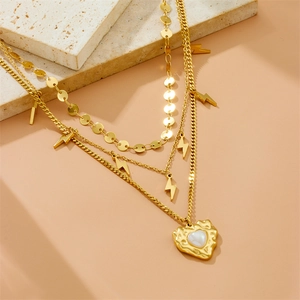 Layered gold necklace featuring lightning charms and a heart pearl pendant on a stone