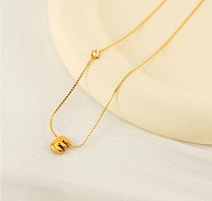 Macro detail of gold bubble letter E pendant necklace with sparkling zircon stone