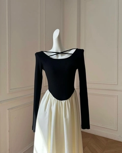 Detailed view of contrasting color dress with criss-cross neckline and pleated skirt