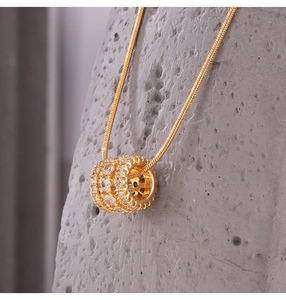 Macro shot of gold cylinder pendant with pavé cubic zirconia on a snake chain