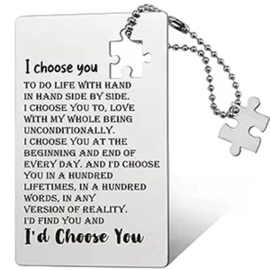 Macro shot of silver stainless steel card set with puzzle pendant and engraved text