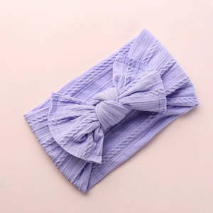 Detail of purple knitted nylon baby headband with soft cable stitch texture and bow