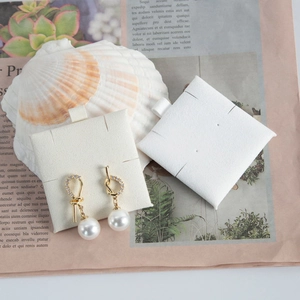 Macro shot of gold pearl earrings with zircon inlay on a white jewelry display card