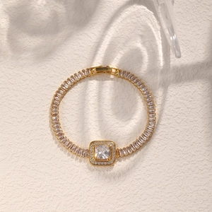 Macro shot of gold bracelet with square transparent gemstone on textured background