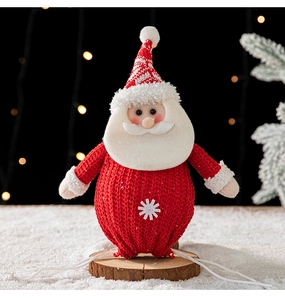Détail d'une figurine du Père Noël tricotée sur socle en bois avec éclairage festif