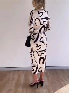 Elegantes cremefarbenes Langarm-Midikleid mit abstraktem Muster in der Rückansicht am Model