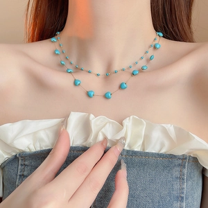 Close-up of double-layer gold necklace with blue heart stones on a model's neck