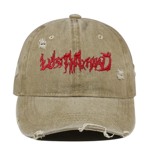 Close-up of red LOST MY HEAD embroidery and distressed holes on khaki washed cotton cap