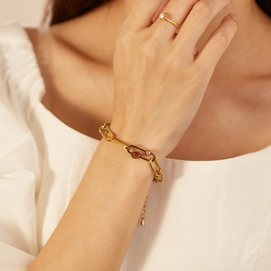 Bracelet maillons trombone doré avec zircons roses et rouges au poignet femme