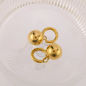 Minimalist hollow gold ball hoop earrings in a textured glass bowl with a soft glow